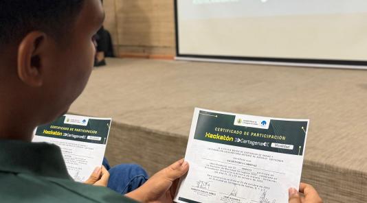 Imagen de un jove sosteniendo en sus manos un certificado de premiación Hackathon dia 3