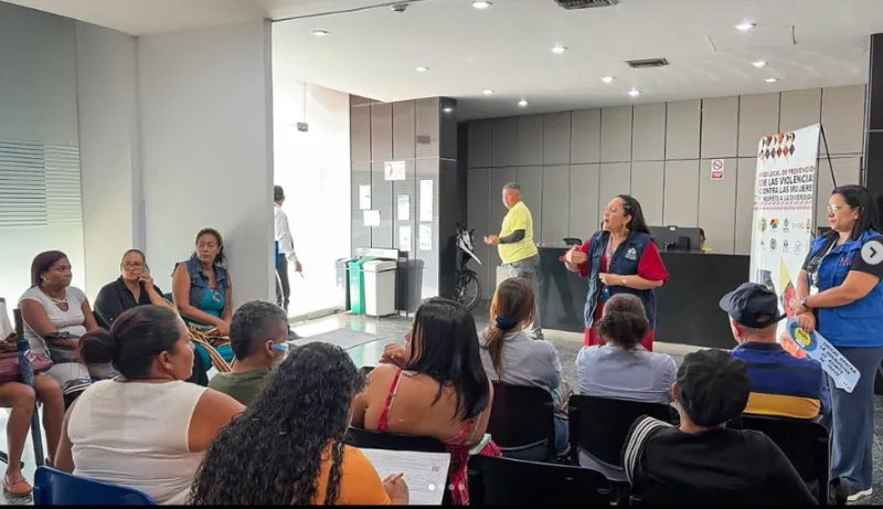 Funcionaria de la Defensoría del Pueblo impartiendo una charla informativa a un grupo de asistentes sentadas en un auditorio en el marco de la conmemoración del 8M