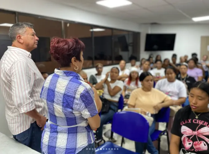 En la imagen se observa a un grupo numeroso de personas atentas en un salón de capacitación, mientras dos instructores de pie dirigen la sesión formativa.