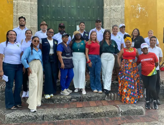 En la imagen se observa a un grupo diverso de funcionarios y líderes comunitarios posando sonrientes en la entrada de un recinto histórico durante la jornada institucional.