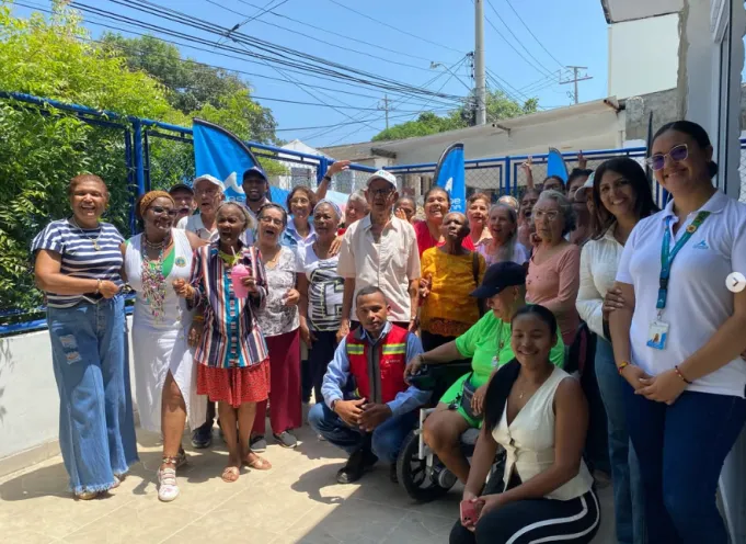 Fotografía al aire libre donde un grupo numeroso de adultos mayores y personal institucional posan sonrientes y alegres frente a la entrada del Centro de Vida San Isidro, acompañados de pancartas. 